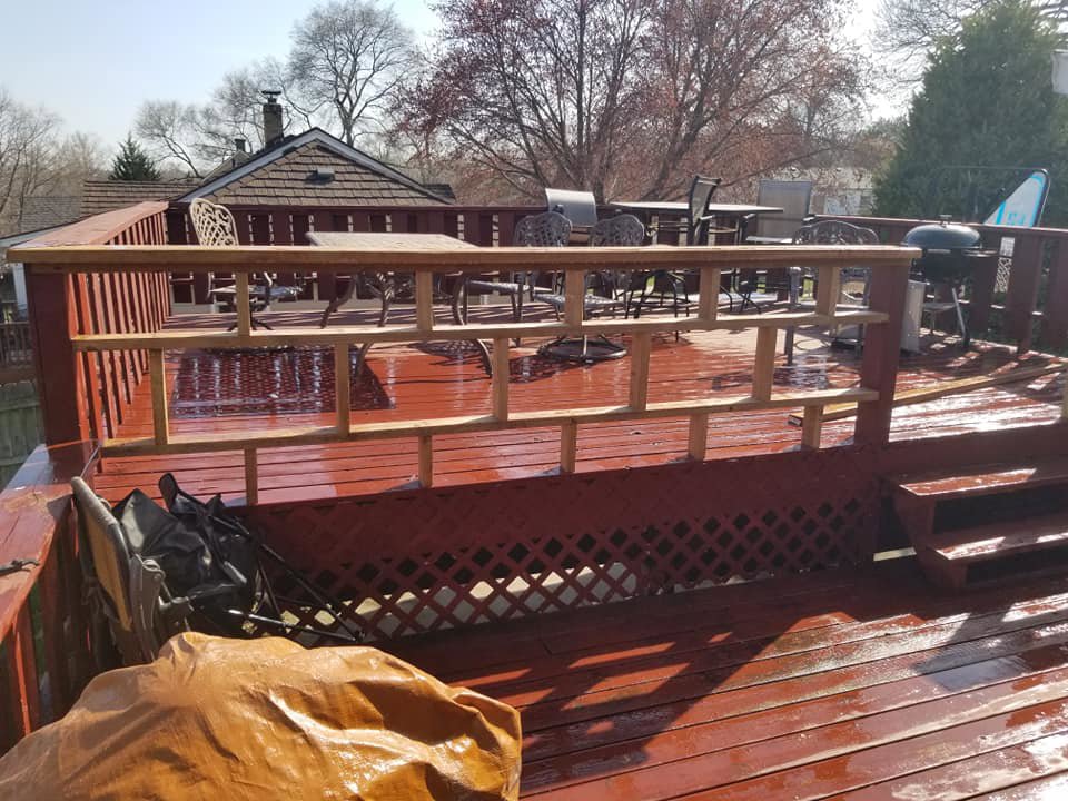 A wooden deck with new railing sections being installed or repaired by Excalibur Home Services in Council Bluffs, IA.