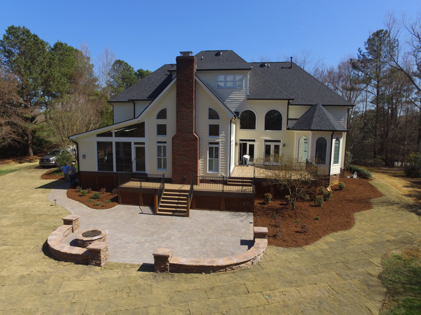 Workers constructing a new deck, screened porch, and paver patio for a home by Raleigh Deck & Screen Porch Builder in Raleigh, NC