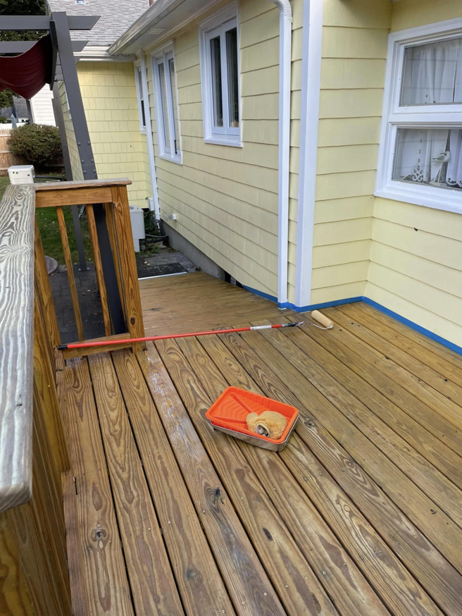 A wooden deck being stained with a roller and tray by Digby Handyman Services LLC in Cranston, RI.