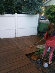 A person staining a wooden deck, a service offered by MDJ Handyman in Salt Lake City, UT.