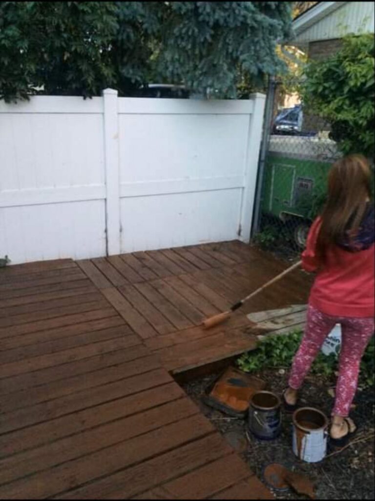 A person staining a wooden deck, a service offered by MDJ Handyman in Salt Lake City, UT.