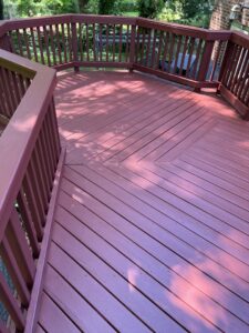 A beautifully stained reddish-brown wooden deck, showcasing a completed project by Quality Painting of Raleigh in Raleigh, NC.