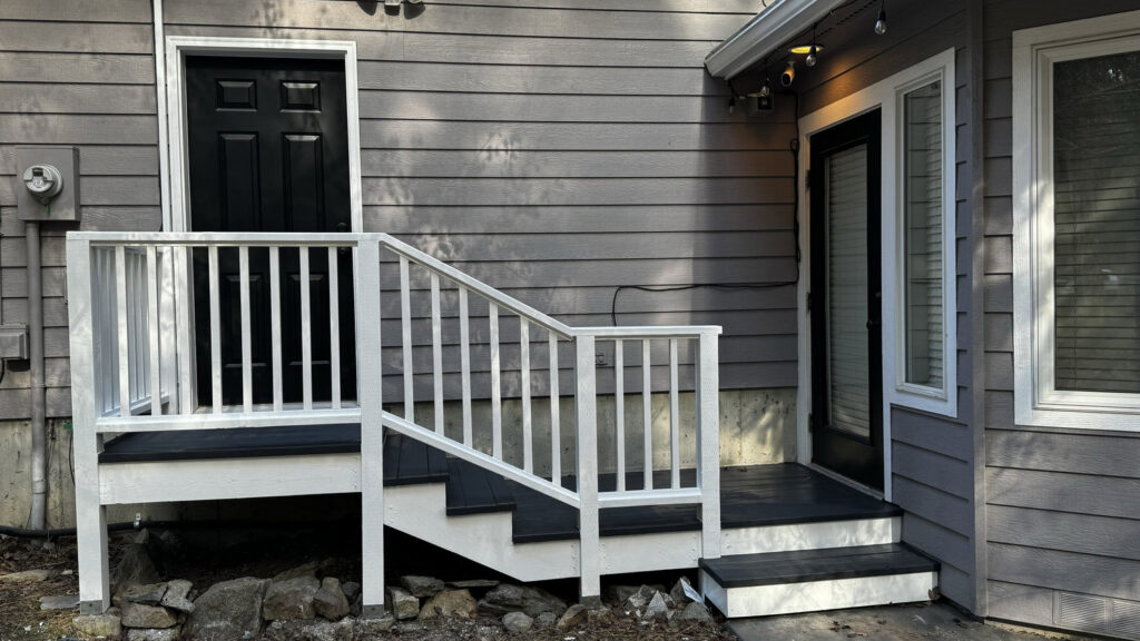 Newly constructed deck and stairs with white railings on a house exterior by Top Shelf Handyman Pros in Post Falls, ID