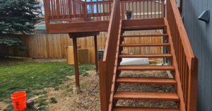 Close-up view of newly stained wooden deck stairs from ground level, a project by All Hung Up LLC in Littleton, CO.