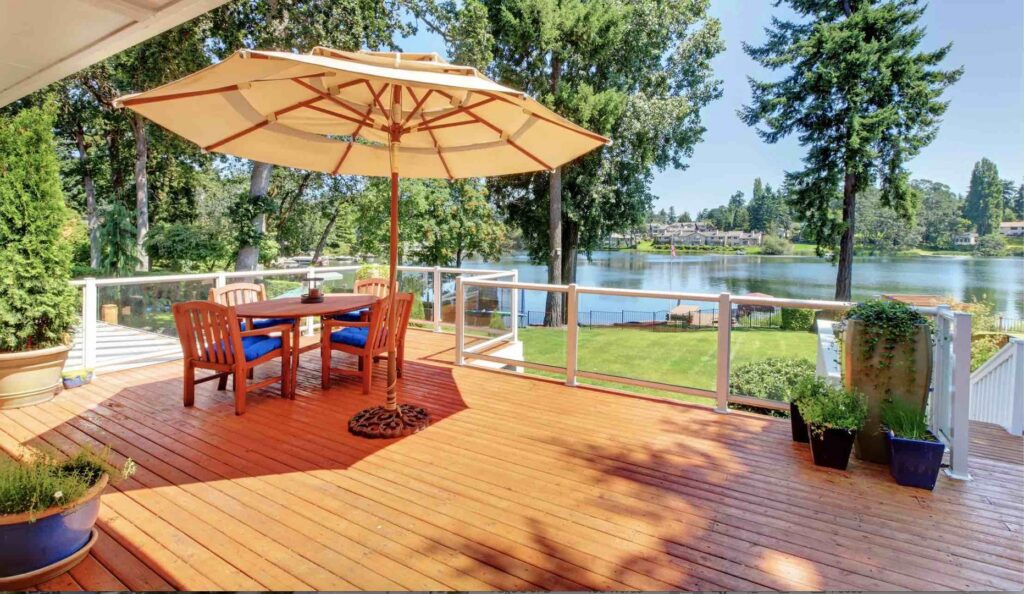 A modern deck with clear glass railings and a lake view by St. Charles Deck in St. Charles, MO