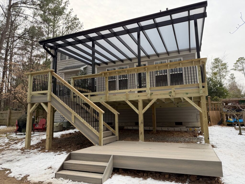 A large outdoor deck featuring a transparent roof cover and stairs, constructed by Elite Xteriors NC in Cary, NC.