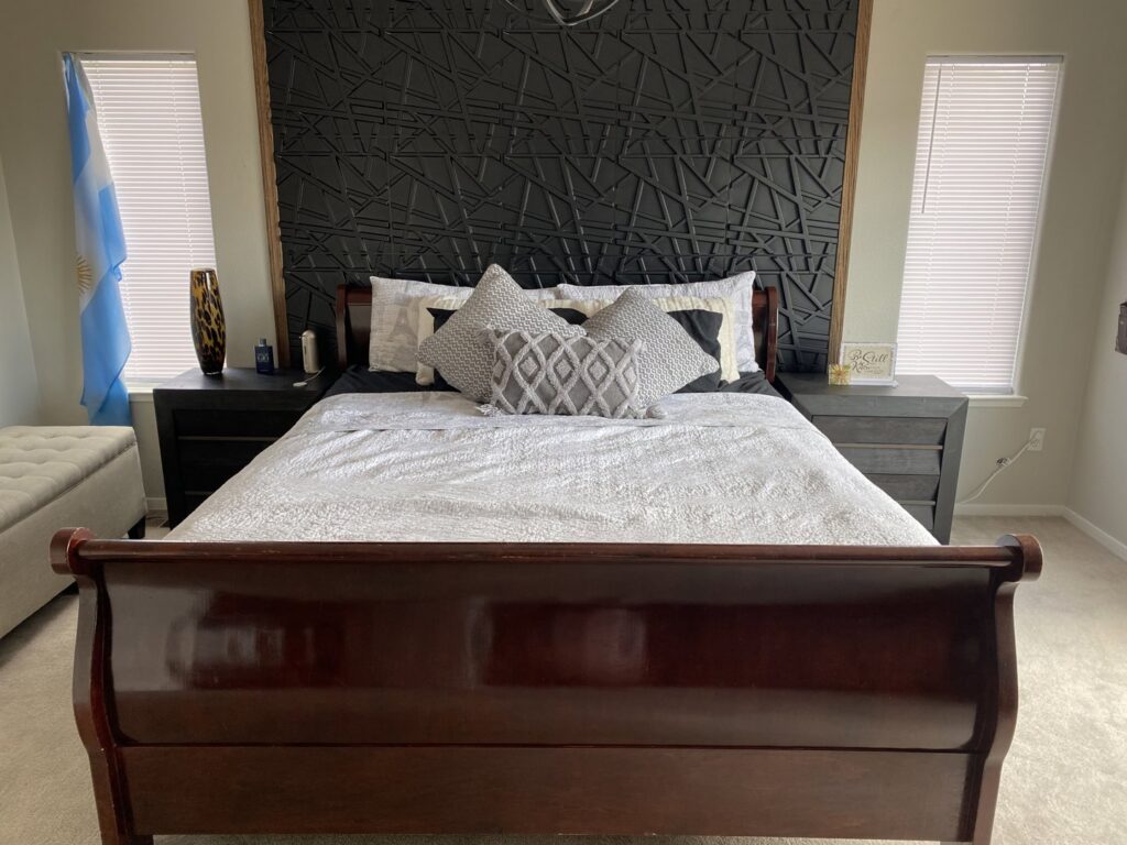 A bedroom featuring a newly installed decorative black wall panel behind the bed by Prospective 1, LLC in Sparks, NV.