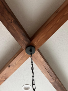 Close-up of decorative wooden ceiling beams and a new light fixture installed by IGM Handyman Services in Meridian, ID.