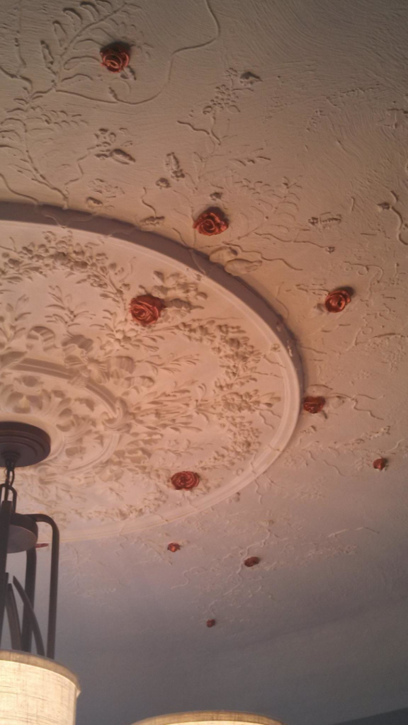 An intricately decorated ceiling with a medallion and rose appliques, installed by Symphonic Painting in Oshkosh, WI.