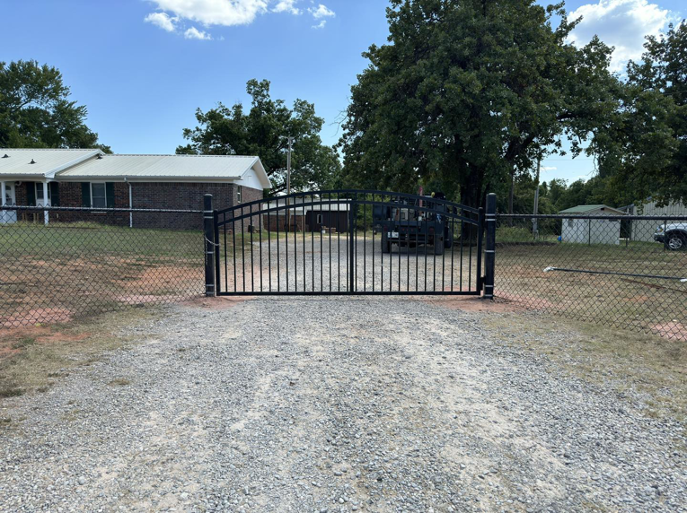 A decorative black metal gate and chain-link fence installed at a property entrance by Herron Fencing LLC in Shawnee, OK.