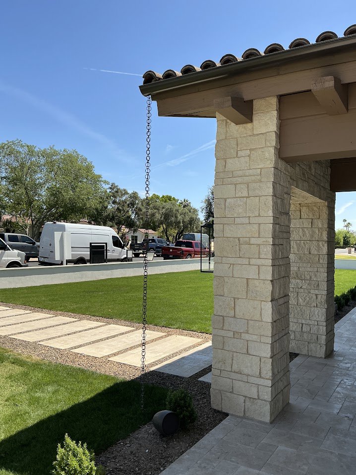A decorative rain chain installed from a gutter on a house, a service provided by Phoenix Rain Gutters and Sun Protection in Glendale, AZ.