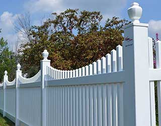 A decorative white vinyl picket fence with ornate posts installed by R & C Fence in Fort Wayne, IN.