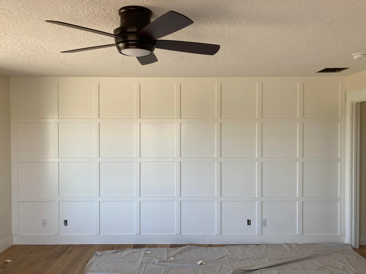 Custom decorative white wall paneling or wainscoting with a ceiling fan, a handyman carpentry service by JMY Construction in Meridian, ID.