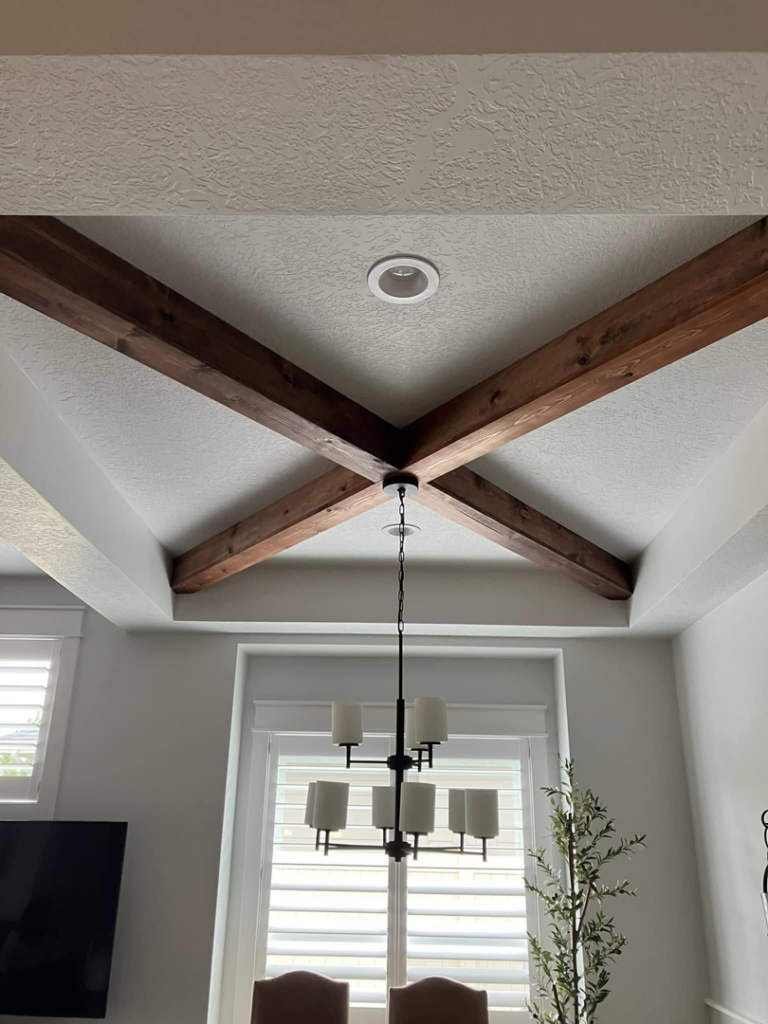 Decorative wooden ceiling beams and a new chandelier installed in a dining room by IGM Handyman Services in Meridian, ID.