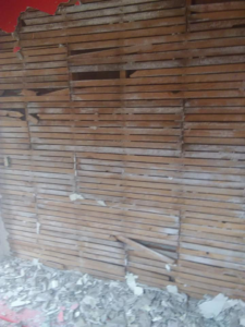 A demolished lath and plaster wall showing exposed wooden lath and debris on the floor by Any Length Improvements in Bowling Green, KY.