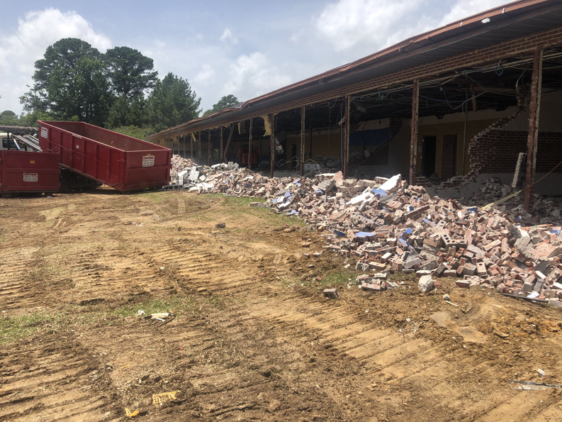 Piles of demolition debris and a large red dumpster at a site serviced by Eco Recycling Group in Macon, GA