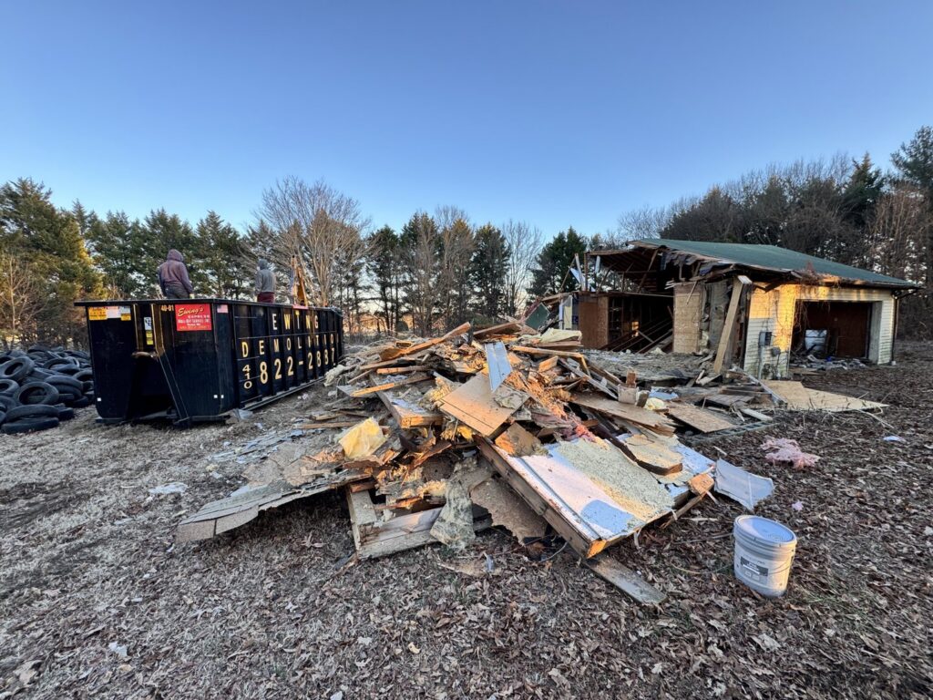 Demolition debris and a large dumpster at a job site by Insta Junk Removal & Demolition LLC in Salisbury, MD