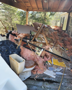 A large pile of demolition debris including insulation, wood, and a toilet on a porch for Patriot Dumpster Rental, Chattanooga, TN.