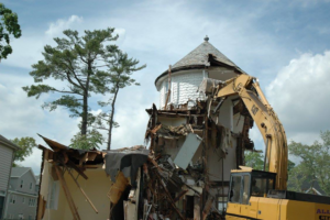 Demolition of a house with a round tower section by an excavator from All Gone Removal Demolition & Junk Dumpster Containers in Toms River, NJ.
