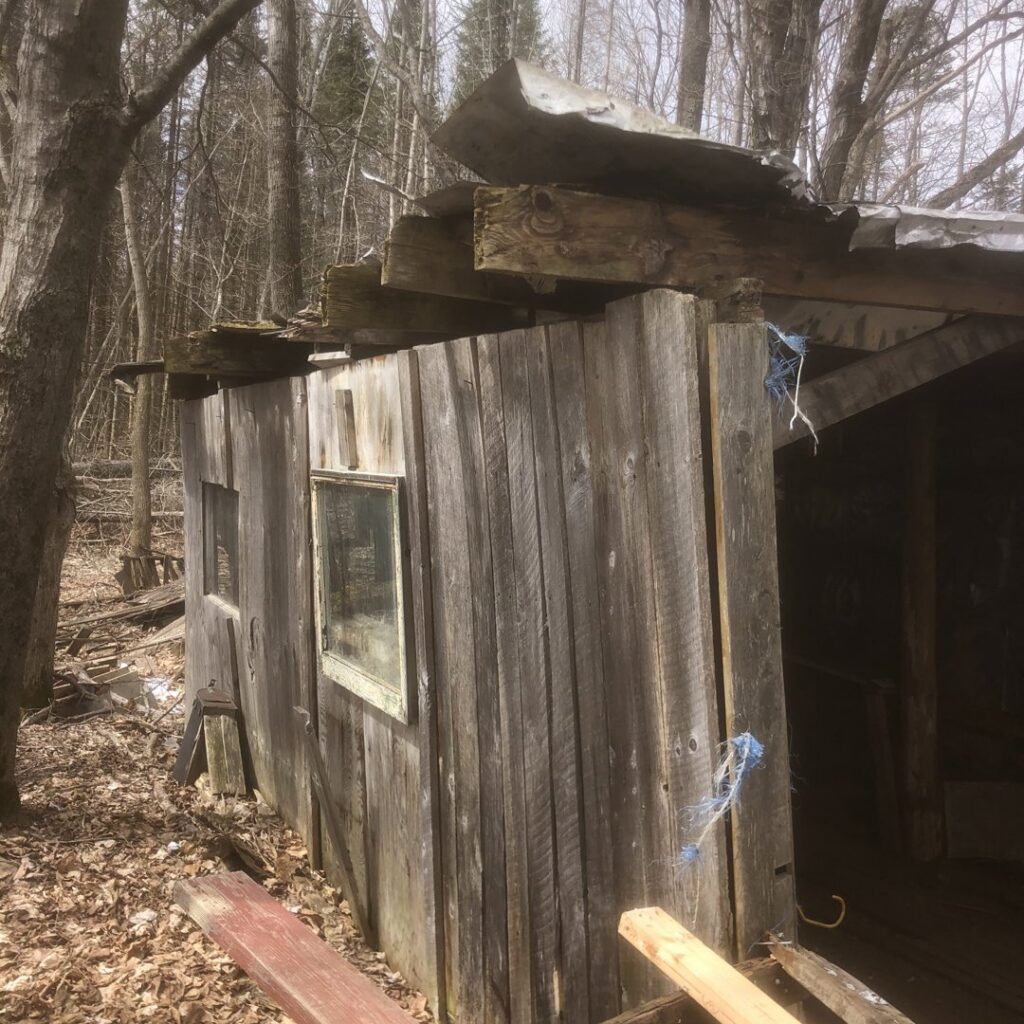 An excavator actively demolishing a mobile home, showing a demolition and hauling service by Tiny's Trash & Hauling Service L.L.C in Williamstown, VT