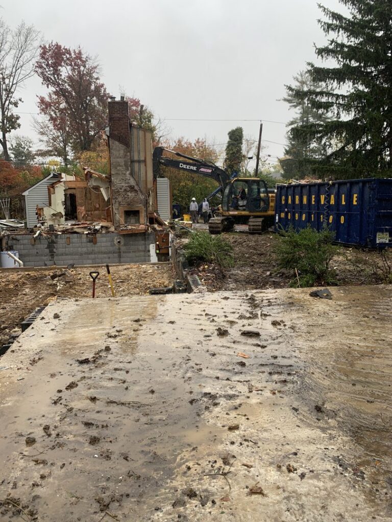 An excavator and an AJ Carnevale Disposal dumpster at a demolition site in Hamilton, NJ