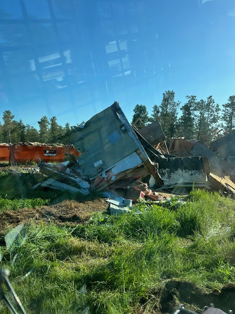 A large pile of demolition waste with an orange Rushmore Dumpster in the background at a job site in Rapid City, SD.