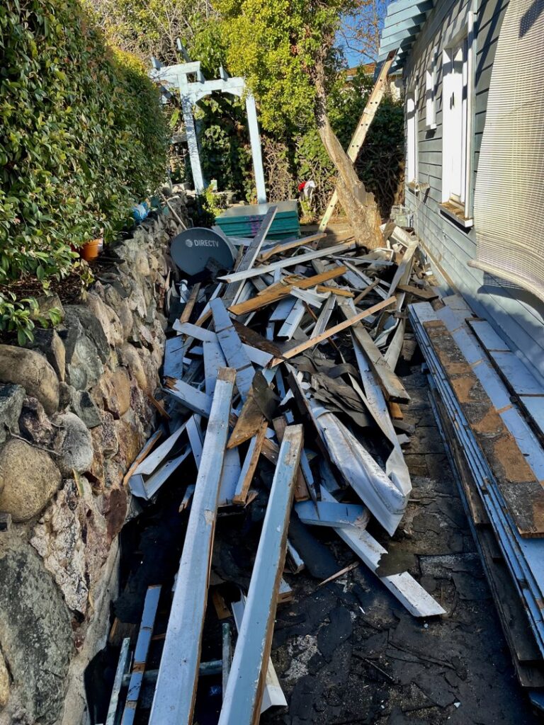 A large pile of wooden planks and demolition debris along an outdoor path for removal by Elite Hauling & Junk Removal in San Diego, CA.