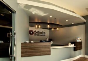 A modern and spacious dental office reception area with a wooden desk and pendant lights, completed by Siegel Construction in Eugene, OR.