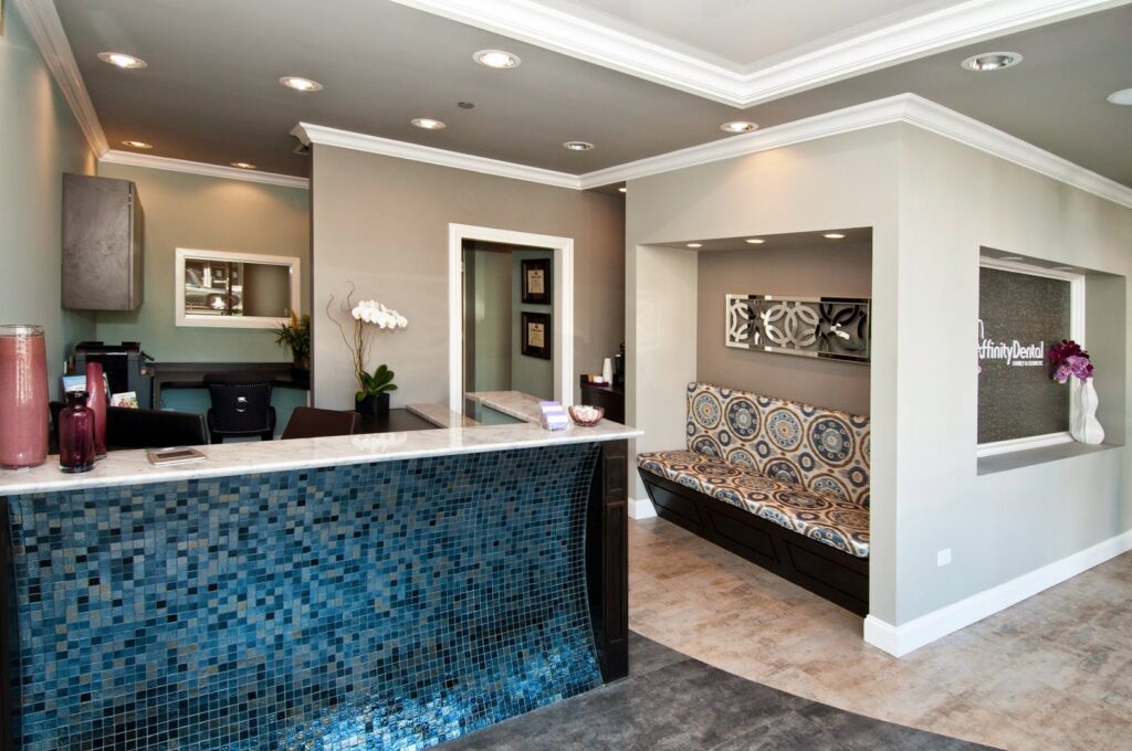 A stylish dental office reception area featuring a blue mosaic tiled desk and comfortable seating, built by Siegel Construction in Eugene, OR.
