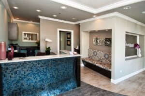 A stylish dental office reception area featuring a blue mosaic tiled desk and comfortable seating, built by Siegel Construction in Eugene, OR.