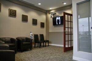 A comfortable dental office waiting area with leather chairs and a wall-mounted TV, completed by Siegel Construction in Eugene, OR.