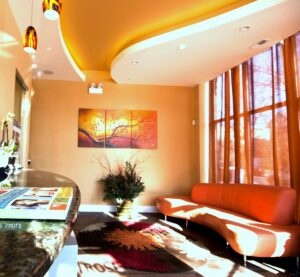 A bright and welcoming dental office waiting room with an orange curved couch and large windows, completed by Siegel Construction in Eugene, OR.