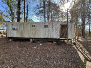 A dilapidated mobile home in a wooded area, ready for demolition or removal by Tote Junk Removal & Demo, LLC in Monroe, LA.