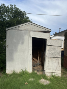 An old, dilapidated wooden shed with debris inside, needing junk removal services from Okc Junk Haul & Delivery in Oklahoma City, OK.