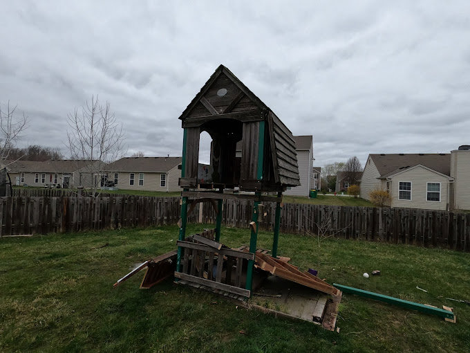 A dilapidated wooden playset in a backyard, ready for removal by Indy Trash Guy in Fishers, IN.