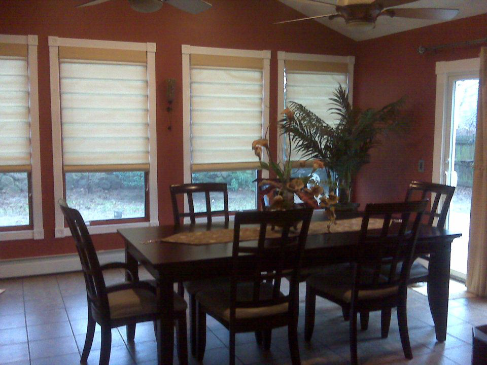 A dining room with newly installed window blinds and ceiling fans by Hammer & Nail Construction in Cumberland, RI.