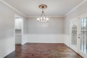 A dining room featuring a chandelier, two-tone painted walls, and hardwood floors, completed by Paradise Found Construction in Cary, NC.