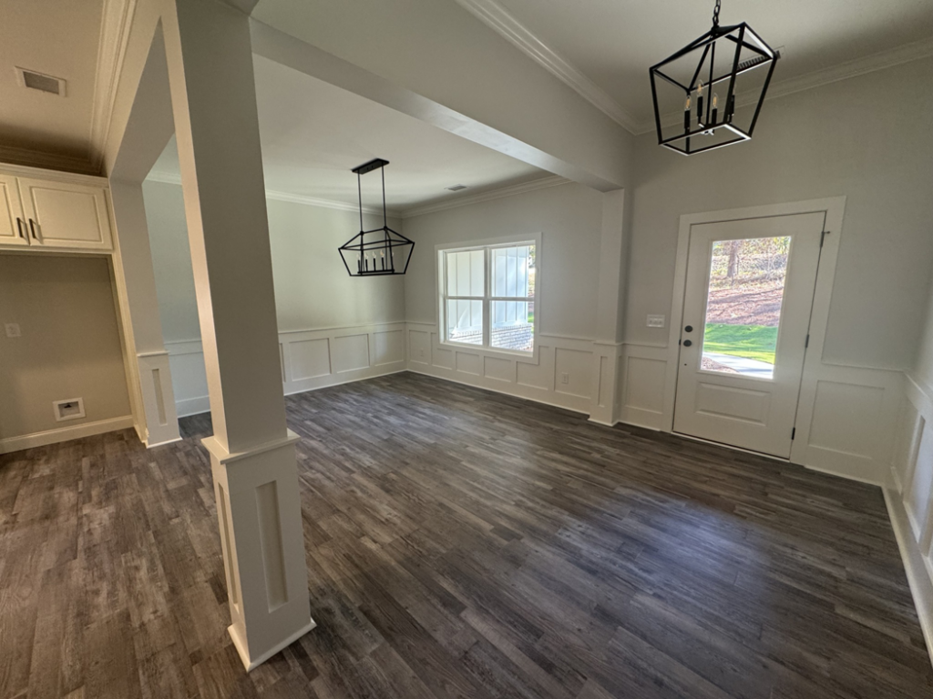 Dining room featuring new flooring, wainscoting, and modern light fixtures installed by Adamson Construction Group in Salem, AL.