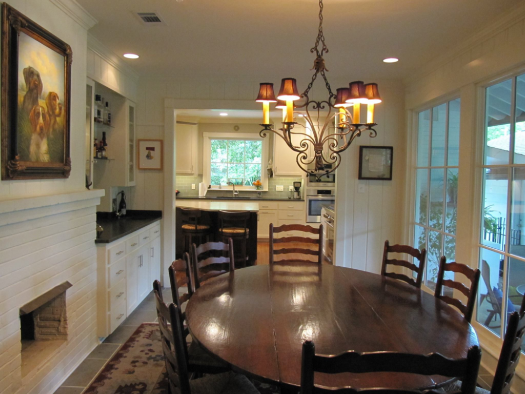 A beautifully remodeled dining room with a large wooden table and chandelier by Jackson Construction in Oak Hills Place, LA