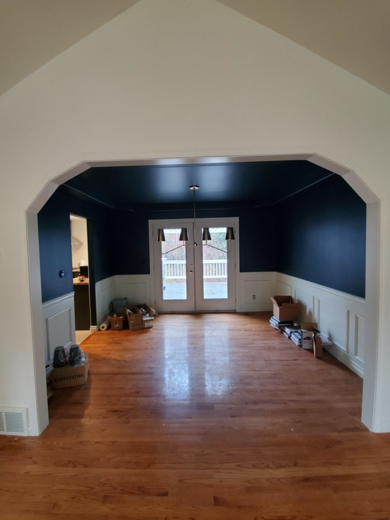 A newly remodeled dining room with dark blue walls, white wainscoting, and hardwood floors by Lilac Remodel Spokane in Spokane Valley, WA.