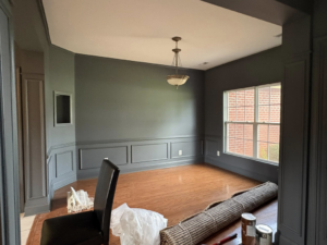 An empty dining room featuring dark grey walls and white wainscoting, painted by Carnelli Painting in Sumter, SC.