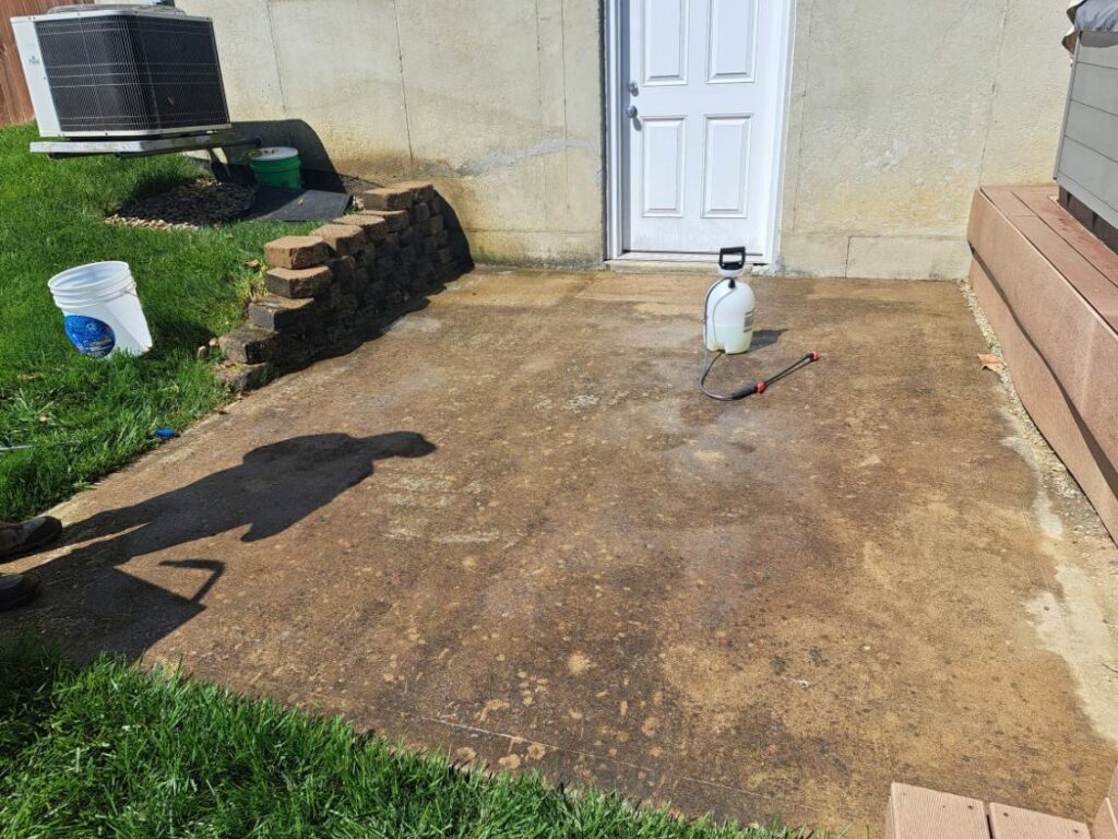 A dirty concrete patio with a sprayer, showing a surface before cleaning by JAMS Property Preservation LLC in Dayton, OH.