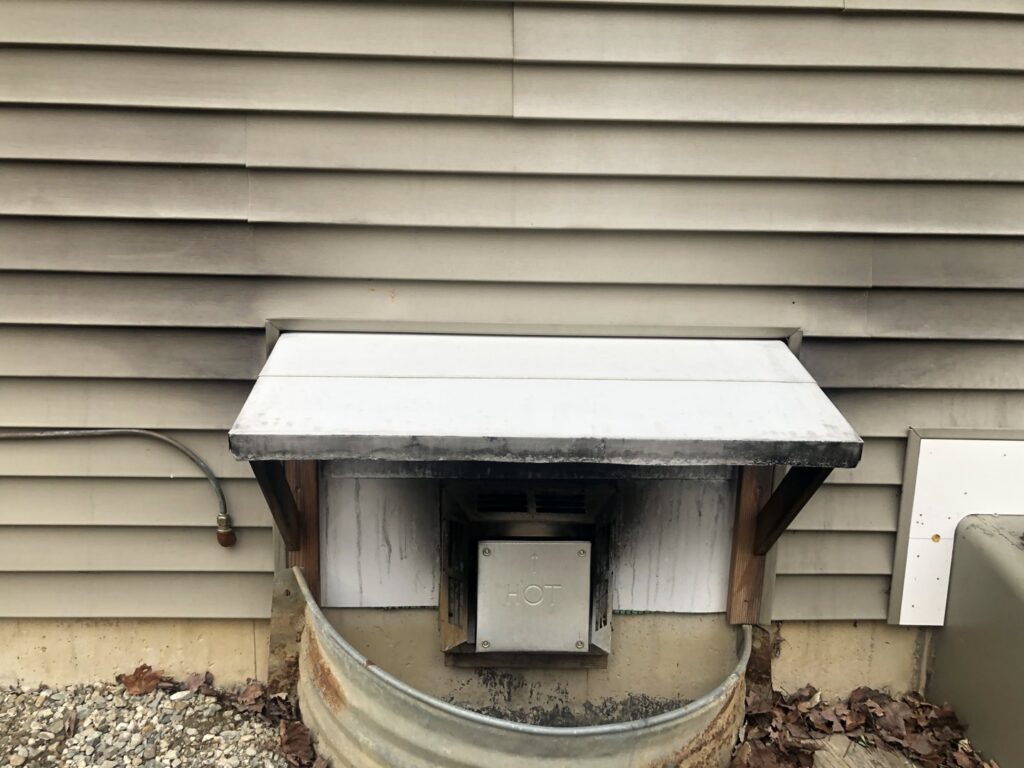 A dirty exterior vent with a small awning, showing an area for handyman cleaning or maintenance by Phoenix's Cleaning Service, LLC in Rutland, VT.
