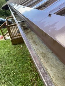 A dirty gutter on a metal roof, ready for cleaning by In Goode Hands LLC in Beckley, WV.