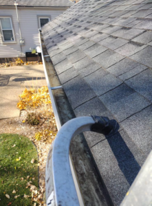 A dirty gutter filled with leaves and debris on a house roof, showing the need for cleaning by Schu Can Do 2-Property Services LLC in Warren, MI.