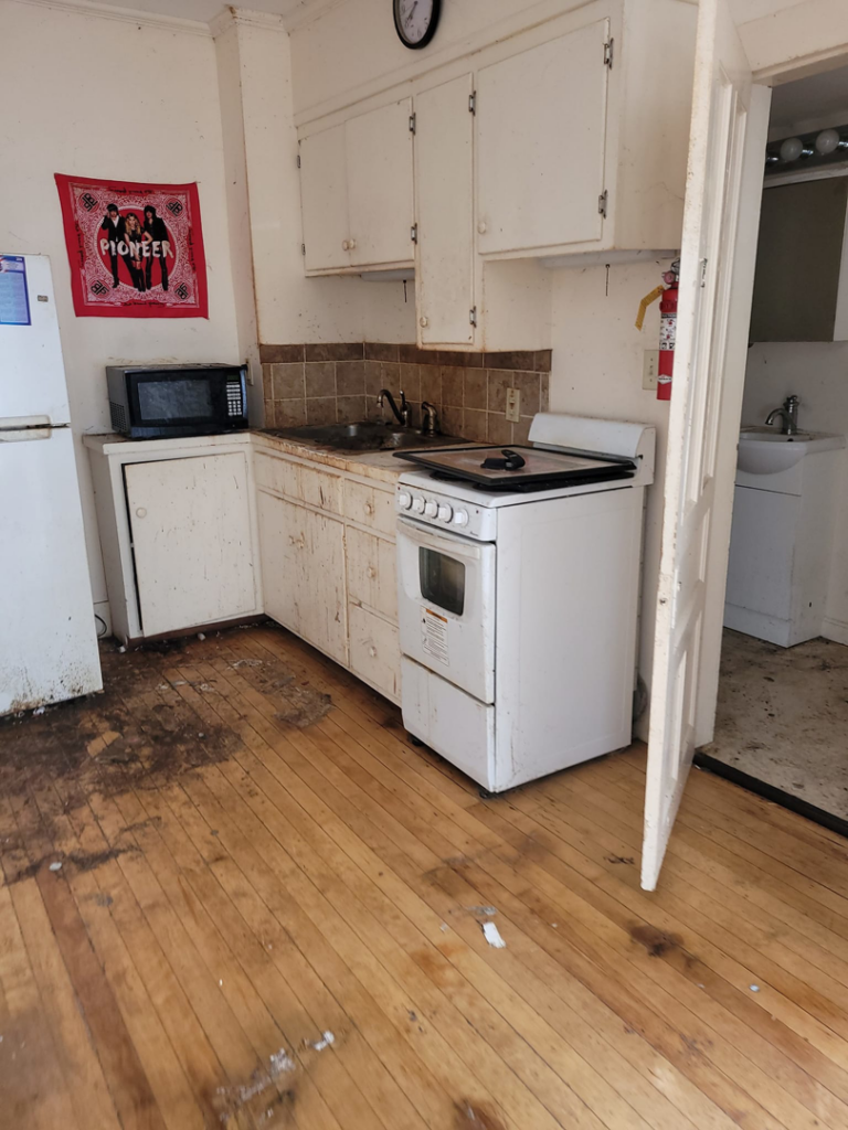 A dirty kitchen with debris on the floor, ready for junk removal by Paul's Trash in East Montpelier, VT.