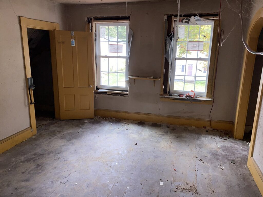 A room with an old fireplace, wood paneling, and a heavily soiled orange carpet, indicating a cleanout or debris removal service by Trash King LLC in Peoria, AZ.
