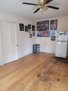 A dirty room with debris on the floor and a refrigerator, ready for junk removal by Paul's Trash in East Montpelier, VT.