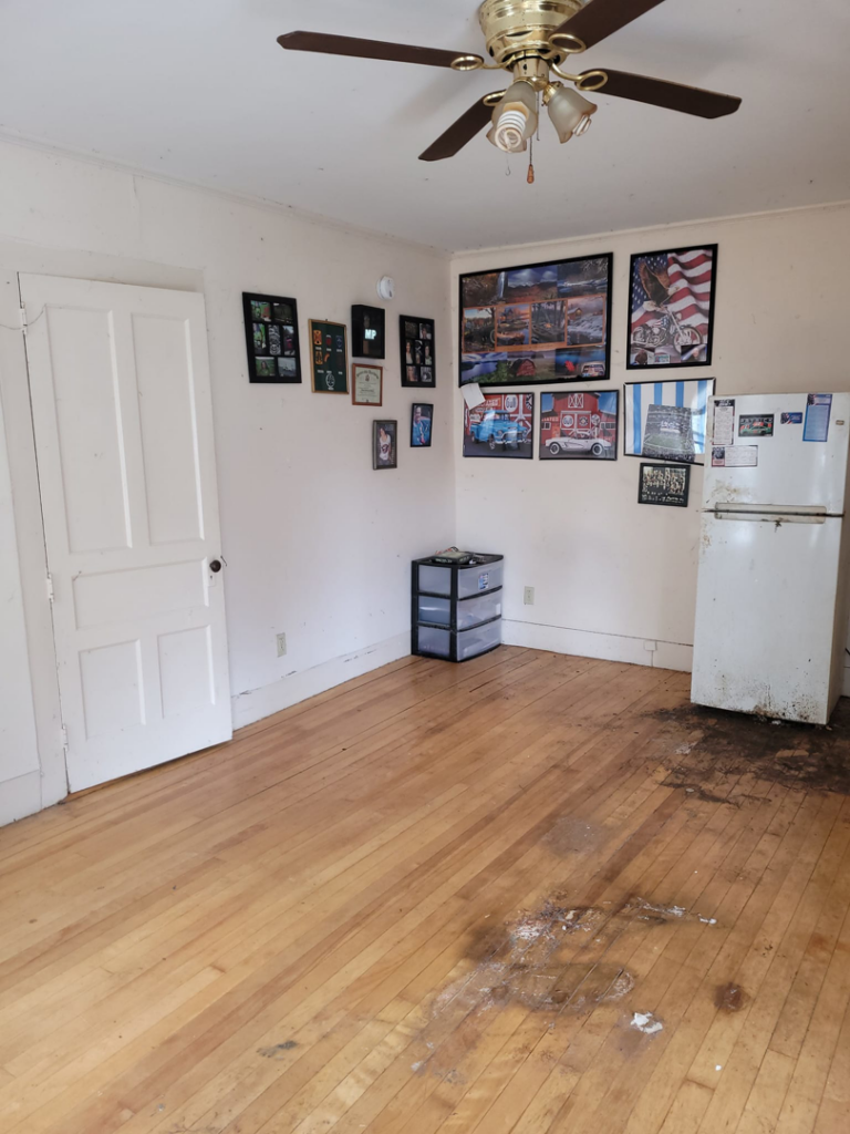 A dirty room with debris on the floor and a refrigerator, ready for junk removal by Paul's Trash in East Montpelier, VT.