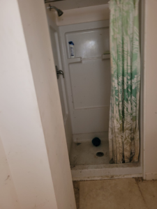 A dirty shower stall in a home needing a cleanout service from Paul's Trash in East Montpelier, VT.
